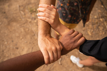 Three hands of different ethnicities grasp each other and form a triangle. Diversity concept