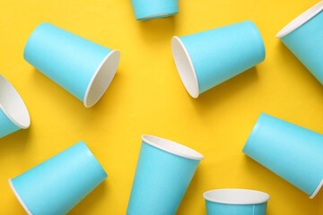 Empty blue cardboard coffee cups on yellow background. Minimalism