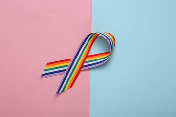 LGBT rainbow ribbon pride tape symbol on pink blue pastel background.