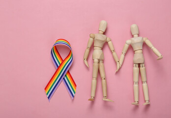 Two puppets hold hands and LGBT rainbow ribbon pride tape symbol on a pink background. Stop...