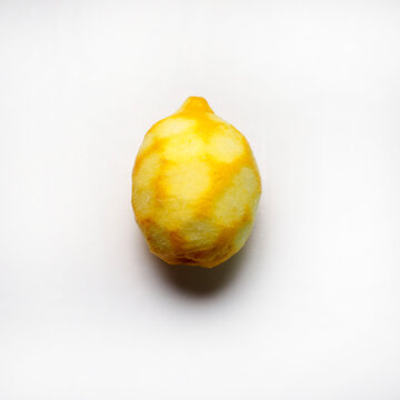 Un limone con la buccia grattugiata isolato su sfondo bianco. Direttamente sopra.