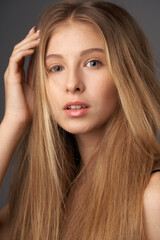 Naklejka premium Natural portrait of young beautiful teen age girl with long straight hair. Female model studio shot against grey background. Pretty girl