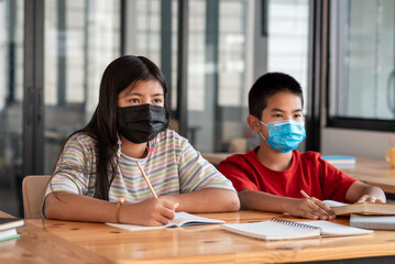 Image of Asian woman and man students are willing to taking notes and wear mask to prevent germ in...