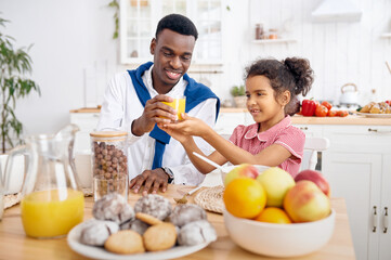 Obraz na płótnie Canvas Father and kid drinks fresh juice on breakfast