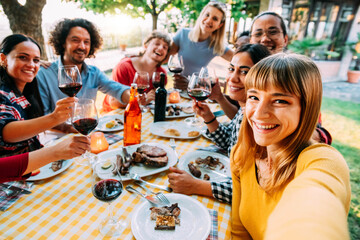 Group of happy friends taking selfie at bbq outdoor dinner in garden restaurant - Multiracial young people eating food and having fun at barbecue backyard home party - Youth and friendship concept