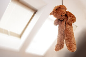 A teddy bear hanging in a noose in the attic room