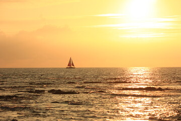 ハワイ島(ビッグアイランド）。一艘のヨットが浮かぶ海に沈む夕日。