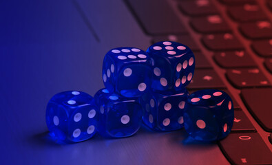 Stack of blue dice on laptop keyboard close up in neon light