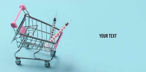 Syringes in a supermarket trolley on a blue background. Copy space