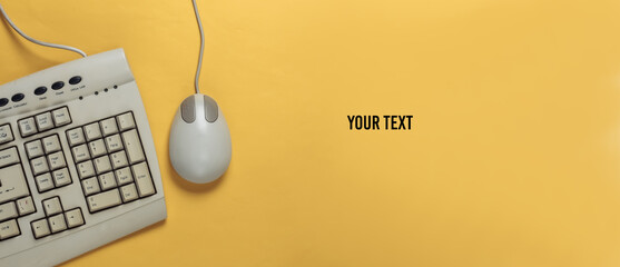 Old-fashioned retro keyboard and pc mouse on yellow background. Retro computer. Top view. Copy space