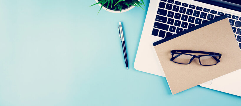 Flat lay of Laptop computer and plant and pen on desk in office, workplace and notebook and glasses and potted tree and book, workspace and copy space, top view, object with above, business concept.