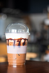 Iced Mocha coffee in plastic take away cup on wood table.