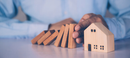 Hands of businessman stop risk about home with block wooden and safety, investment and insurance...