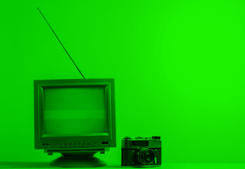 Antenna old-fashioned retro tv receiver and film camera in green neon light
