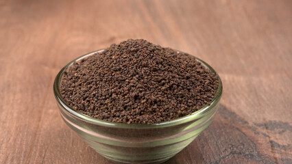 Black Tea Powder or dry dust tea powder, chai patti isolated in wooden bowl with Cardamom, Clove and Ginger.