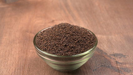 Black Tea Powder or dry dust tea powder, chai patti isolated in wooden bowl with Cardamom, Clove and Ginger.