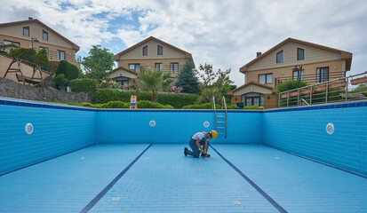 Repairman is repairing pool with equipment. Pool maintenance style.
