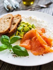 Breakfast - smoked salmon, cottage cheese and avocado on wooden table
