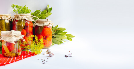 Glass jars with homemade pickled tomatoes, sealed with metal lid on white background. pickled cucumbers, dill sprigs and bay leaves. Country style isolated banner with text area. copyspace. 