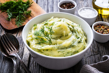 Puree - mashed potatoes with dill in bowl on wooden table