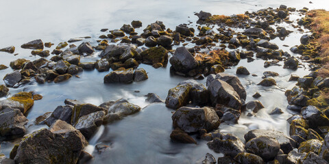 Long exposure of rocks covered with moss in a river in Iceland