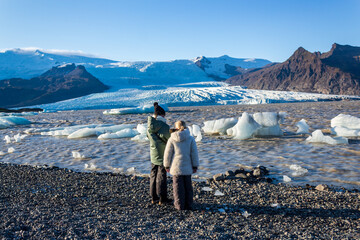 Children watching floating icebergs in the Fjallsárlón Glacier Lagoon in front of the...