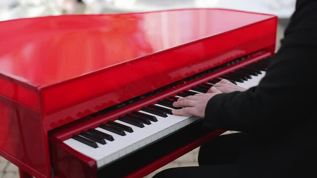 Pianist plays beautiful red grand piano. Romantic atmosphere, perfect date. Hands as young man sits at grand piano and plays.