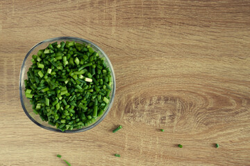 Green garlic arrows in a transparent plate on wooden background