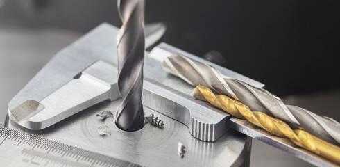 drill bit make holes in steel billet on industrial drilling machine with ruler and caliper. Metal...