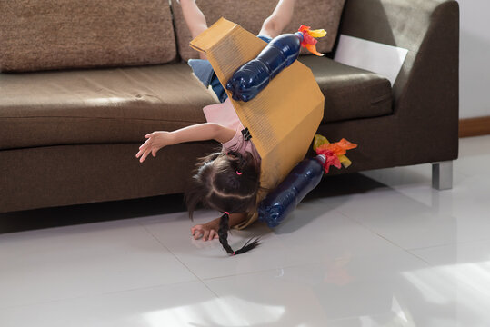 Asian child accident falling off the couch after playing in an astronaut costume