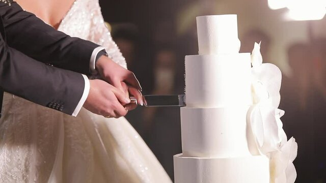 Cut the wedding cake. The bride and groom cut the wedding cake. Detail of wedding cake cutting by newlyweds