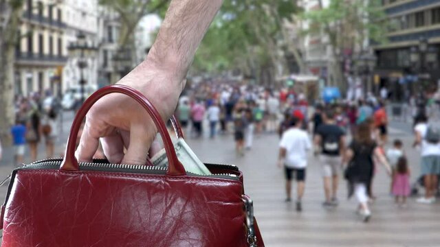 Hand stealing wallet with money from inside a purse in Barcelona