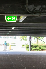 Green exit sign with running person and green arrow shows guidance system signage in a parking lot...