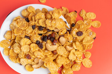 Cornflakes honey caramel homemade with grains, currant, cashew nut, dried strawberries and white sesame healthy food snack on a white plate close up and Macro copy space.