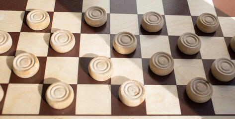 wooden chessboard with white checkers on a light surface. Mind games, mental development and...