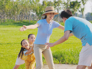 Happy family of four playing games in the park