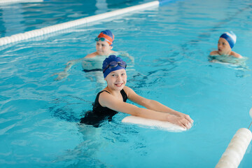 A group of boys and girls train and learn to swim in the pool with an instructor. Development of...