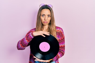 Beautiful hispanic woman wearing hippie style holding vinyl disc depressed and worry for distress, crying angry and afraid. sad expression.