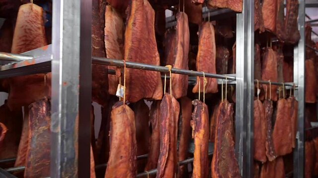 Cured meat hang from a rack at meat processing plant. Traditional food. Smoked sausages meat hanging. High quality FullHD footage
