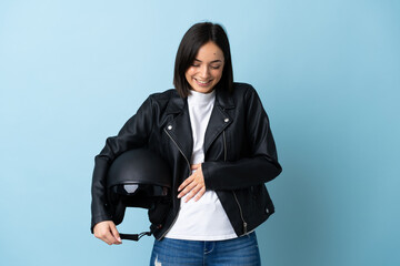 Woman holding a motorcycle helmet isolated on blue background smiling a lot