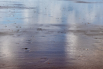 Remnant of water on the sand on the beach with some footsteps, sunny day in Hargen aan Zee, North Holland, Netherlands