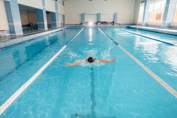 A young athlete trains and prepares for swimming competitions in the pool. Healthy lifestyle.