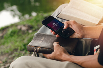 Two young people searching the Bible on their smartphones. Ready to study the Bible in the...