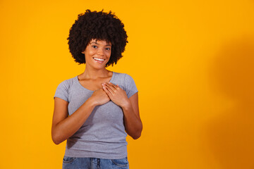 Grateful hopeful happy black woman holding hands on chest feeling pleased thankful, expressing...