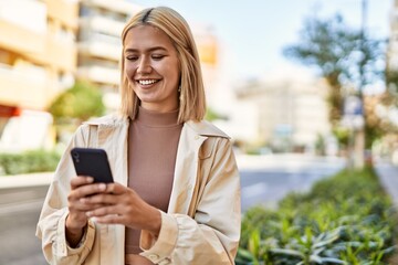Fototapeta premium Young blonde girl smiling happy using smartphone at the city.