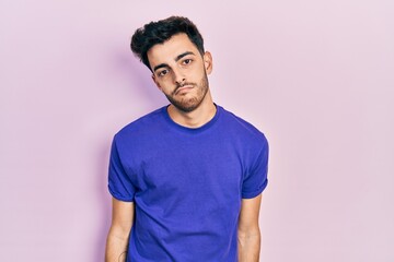 Obraz premium Young hispanic man wearing casual t shirt looking sleepy and tired, exhausted for fatigue and hangover, lazy eyes in the morning.