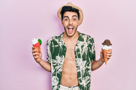 Young hispanic man wearing summer style holding ice cream celebrating crazy and amazed for success with open eyes screaming excited.