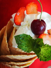 Summer dessert on red background, ice cream with fruits in waffle cones