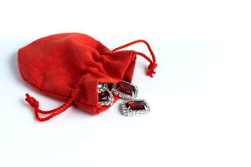 A red pouch on a white background with gemstones scattered on it