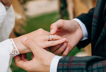 Obraz na płótnie Canvas groom plaid suit puts ring bride hand